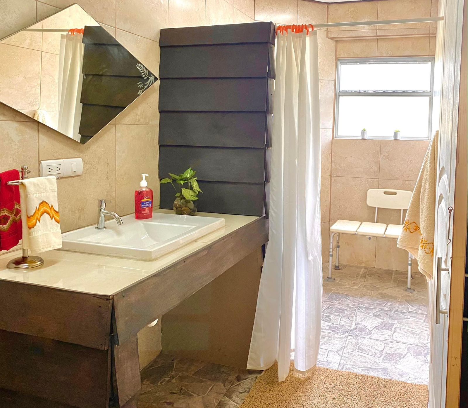 Baño amplio con lavatorio, espejo y ducha con banca